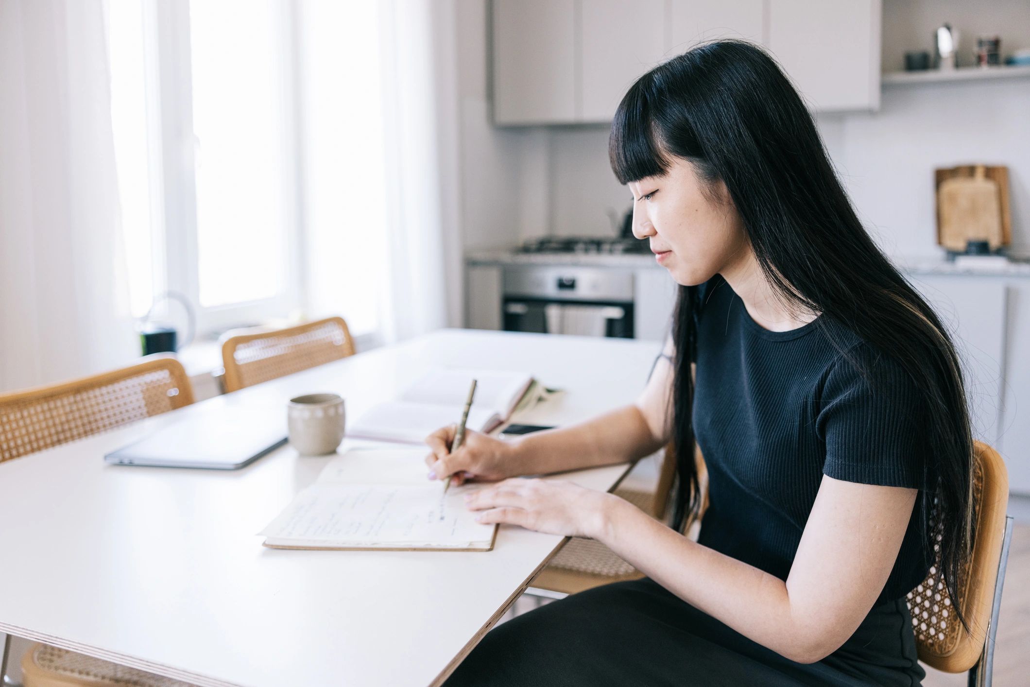 Persona escribiendo en un cuaderno junto a una taza de café